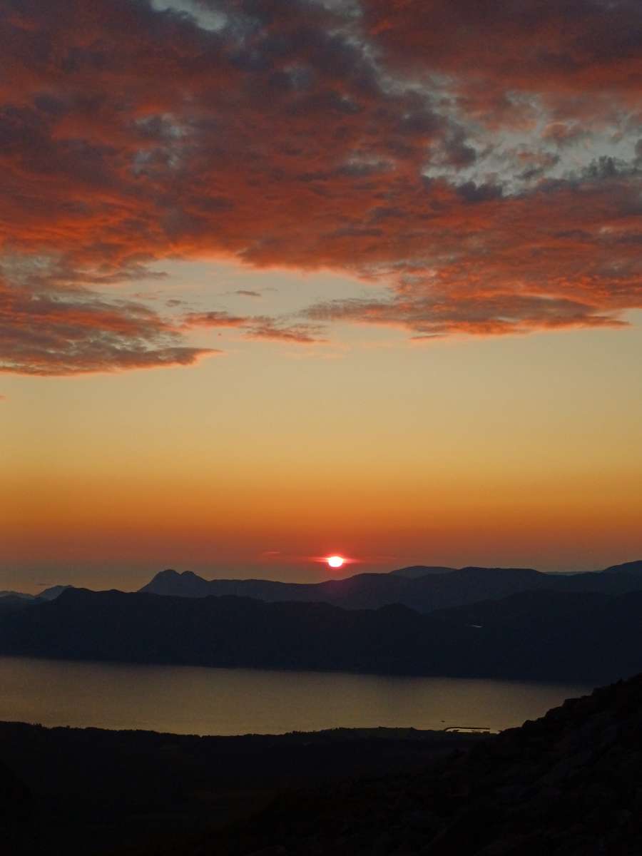 Raud solnedgang over fjord og fjell